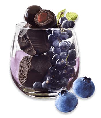 wine glass filled with dark chocolate chunks, grapes, and blueberries