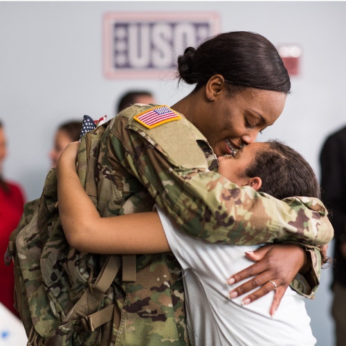 service member hugging her child