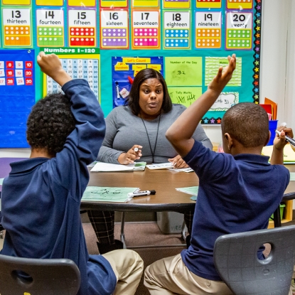 children raising their hands in class