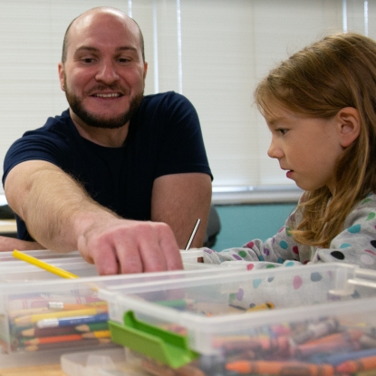 teacher smiling while drawing with student