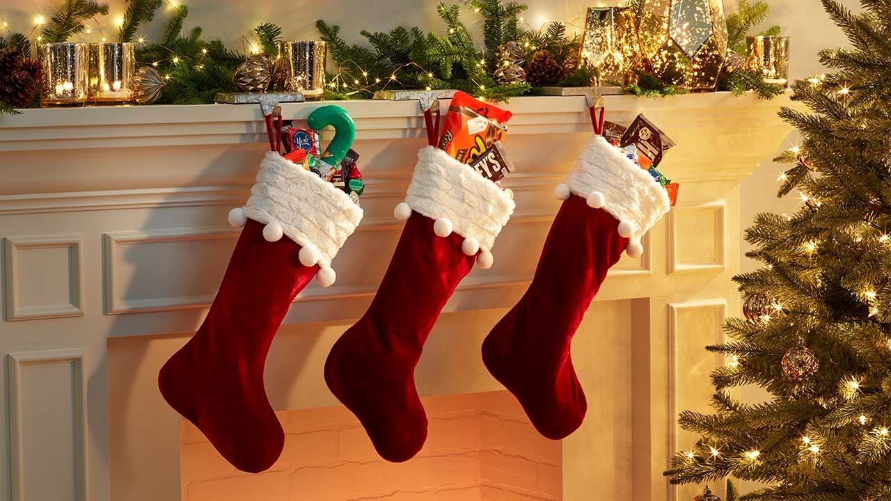 christmas stockings filled with assorted hersheys candys above fireplace