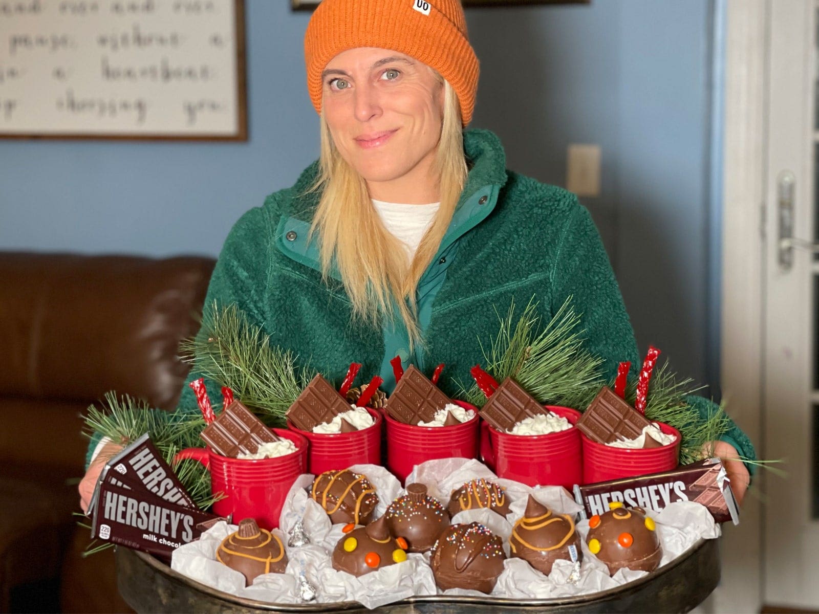 audrey mcclelland holding tray of hot cocoa bomba and filled mugs