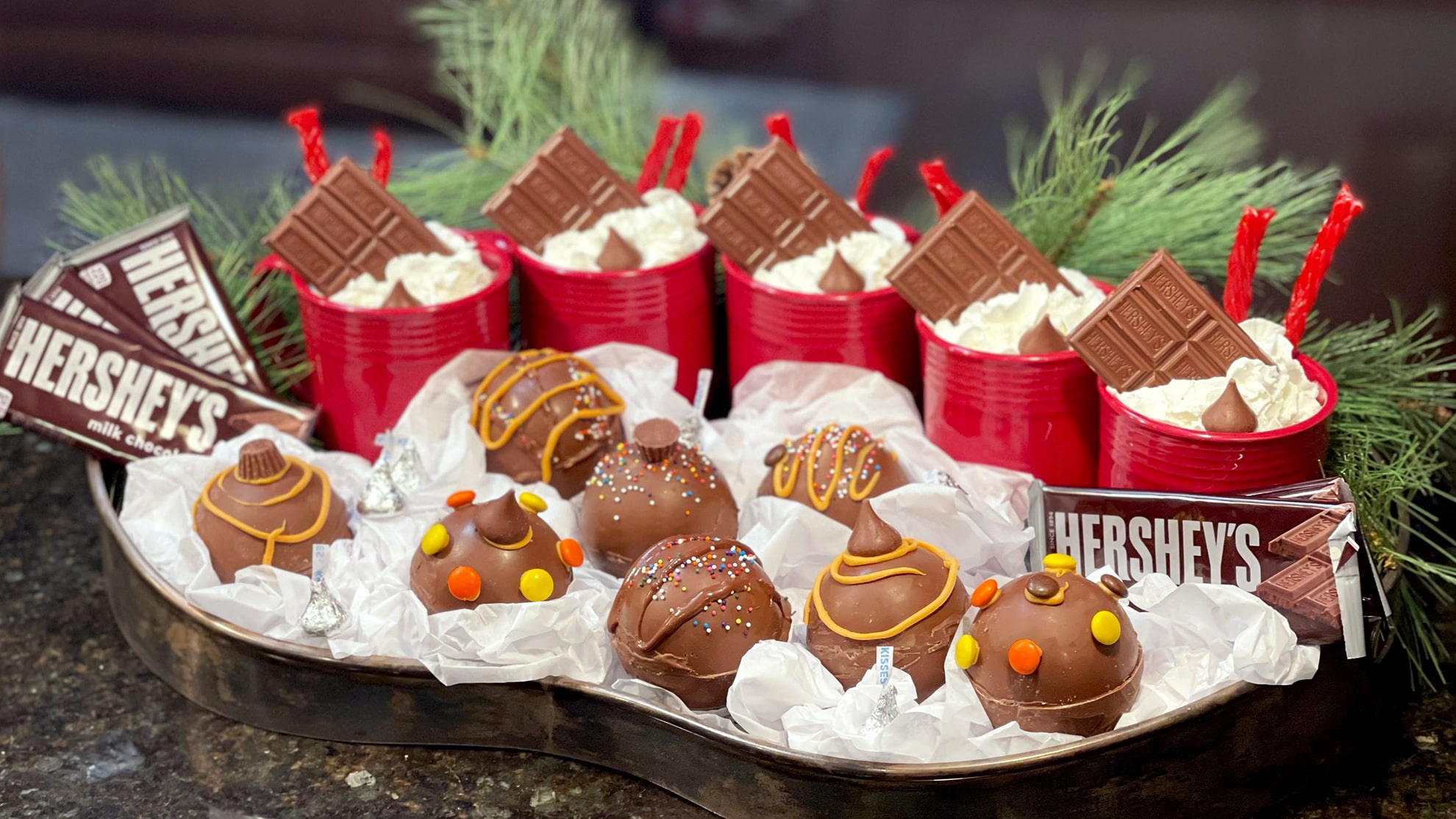 hot cocoa bombs in front of mugs on a table