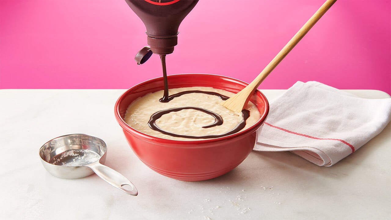 pouring hersheys chocolate syrup into pancake batter