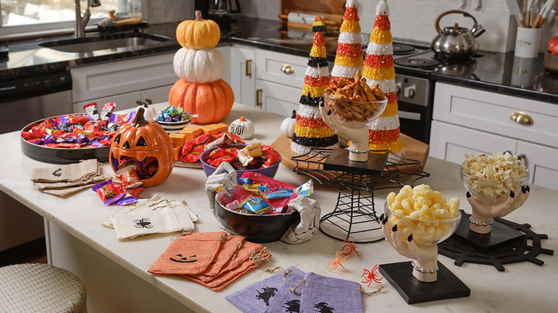 kitchen island topped with halloween decorations and bowls of candy and snacks