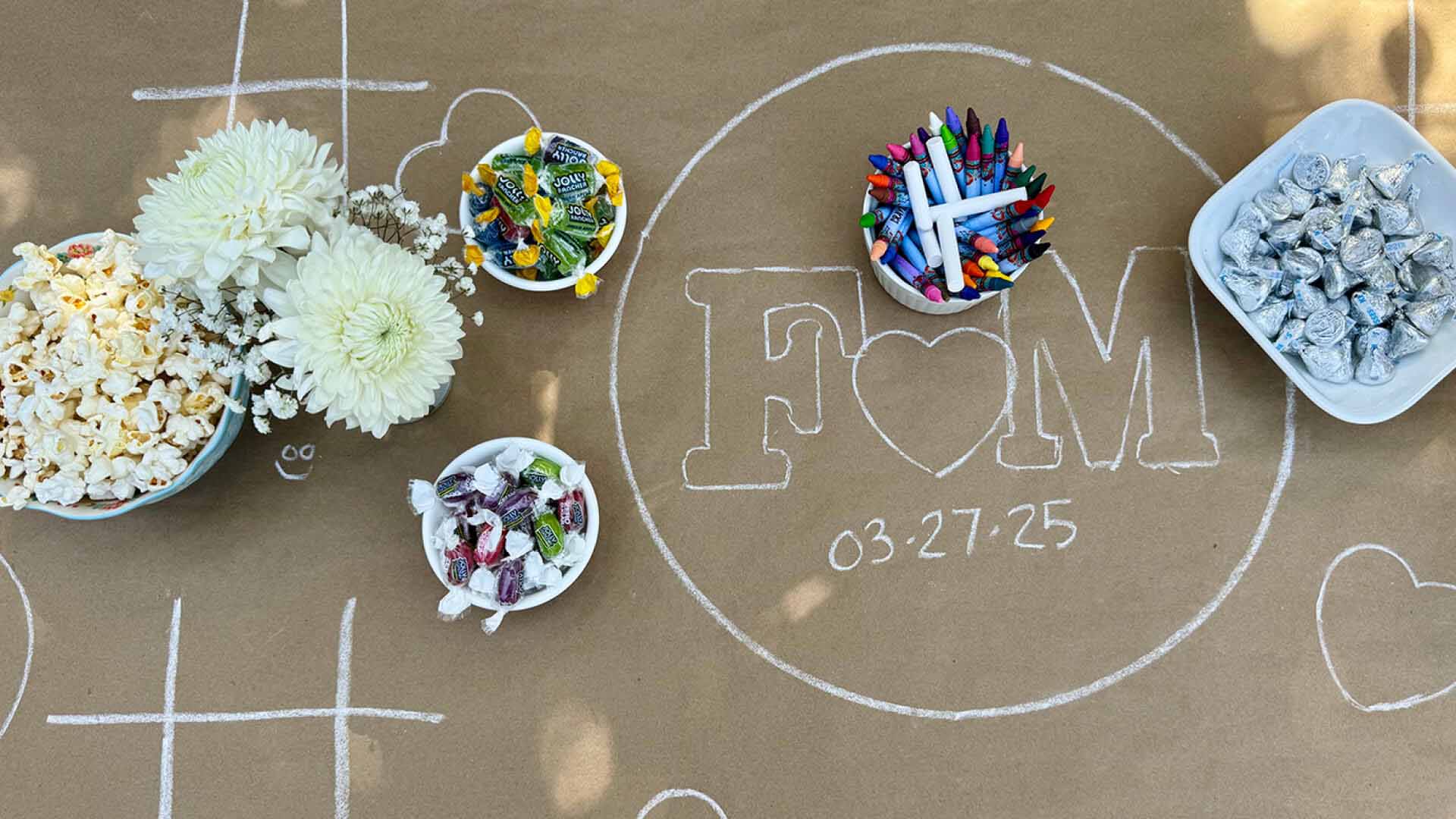 kids activity table decorated with drawings and bowls of candy, popcorn, and flowers