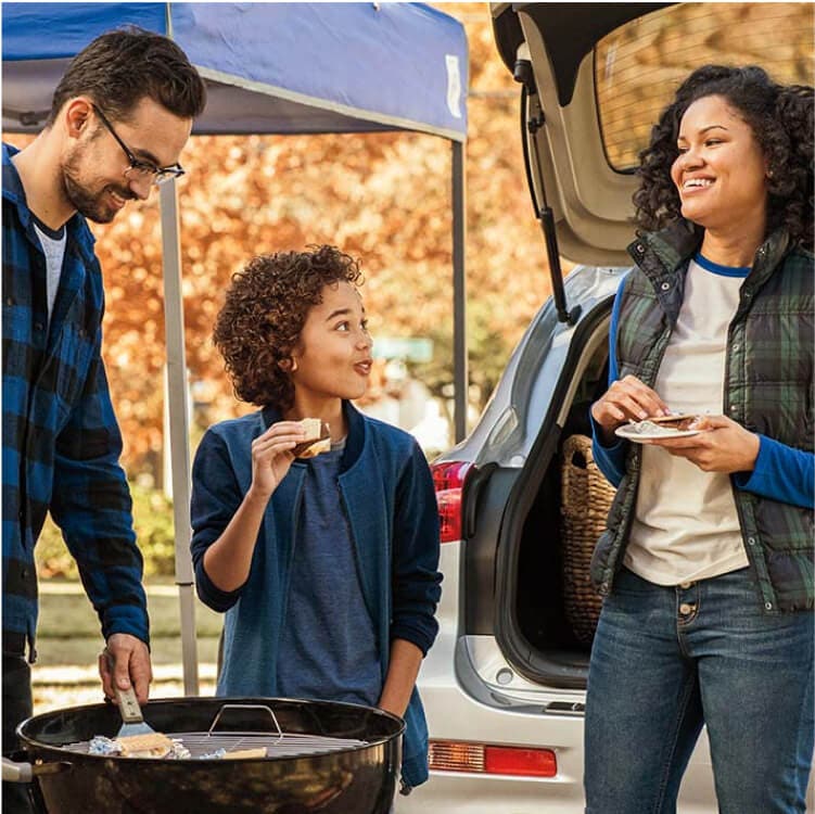 family eating around a grill at a tailgate