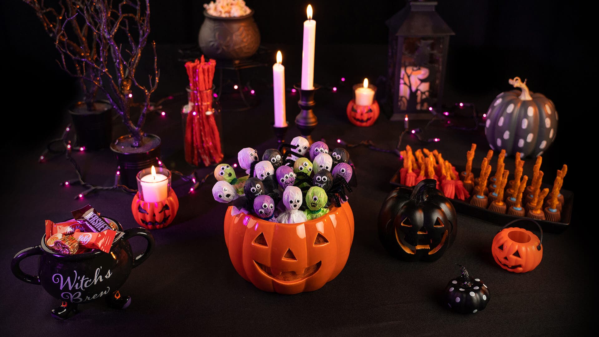 halloween decorated table with monster and ghost lollipops in pumpkin in the center