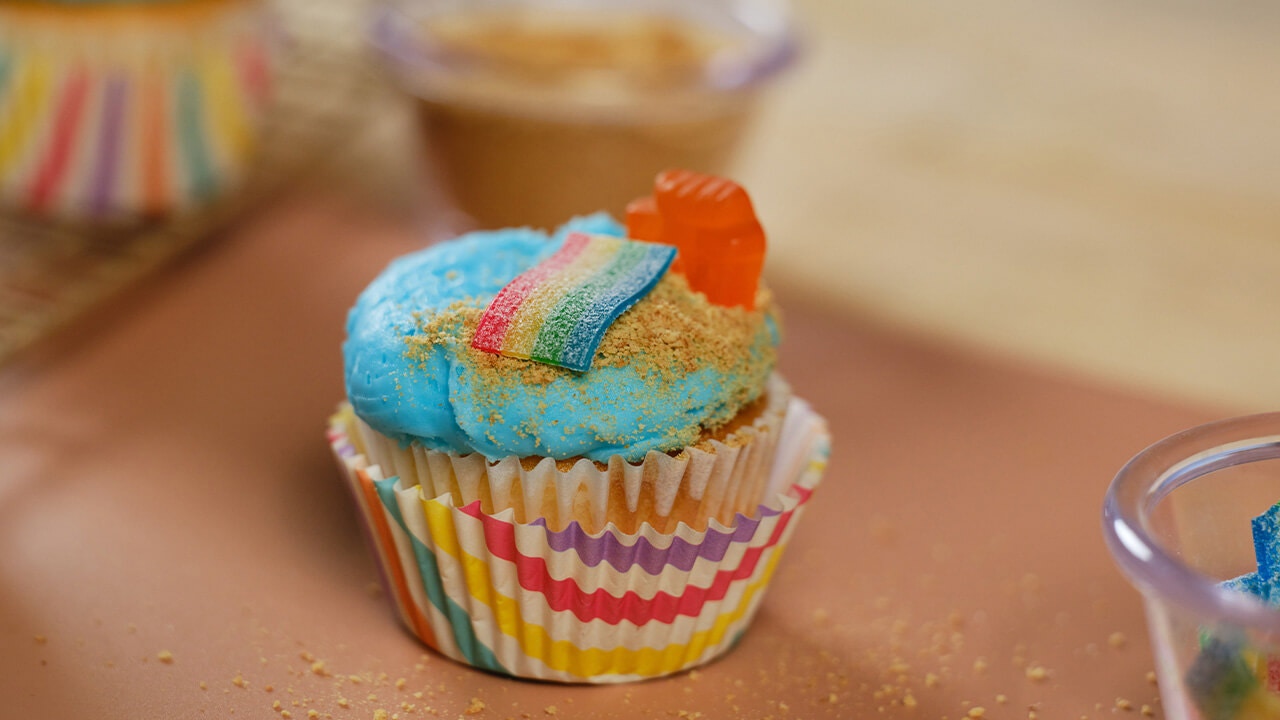 cutting and placing sour strips candy piece on top of the cupcake