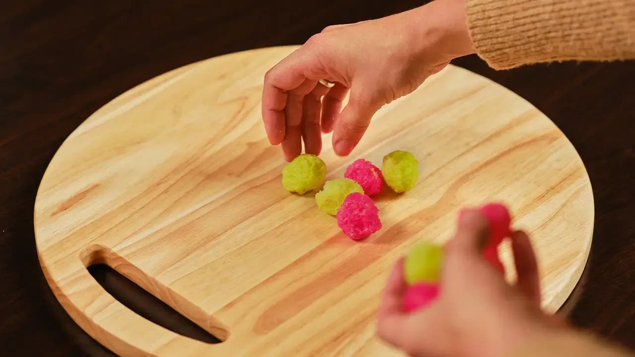 A hand placing candy onto a wooden board