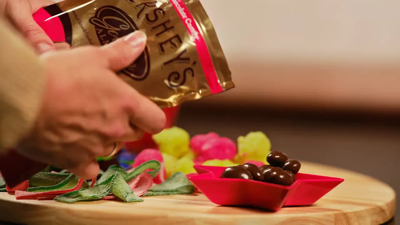 Chocolate covered almonds being poured into a bowl