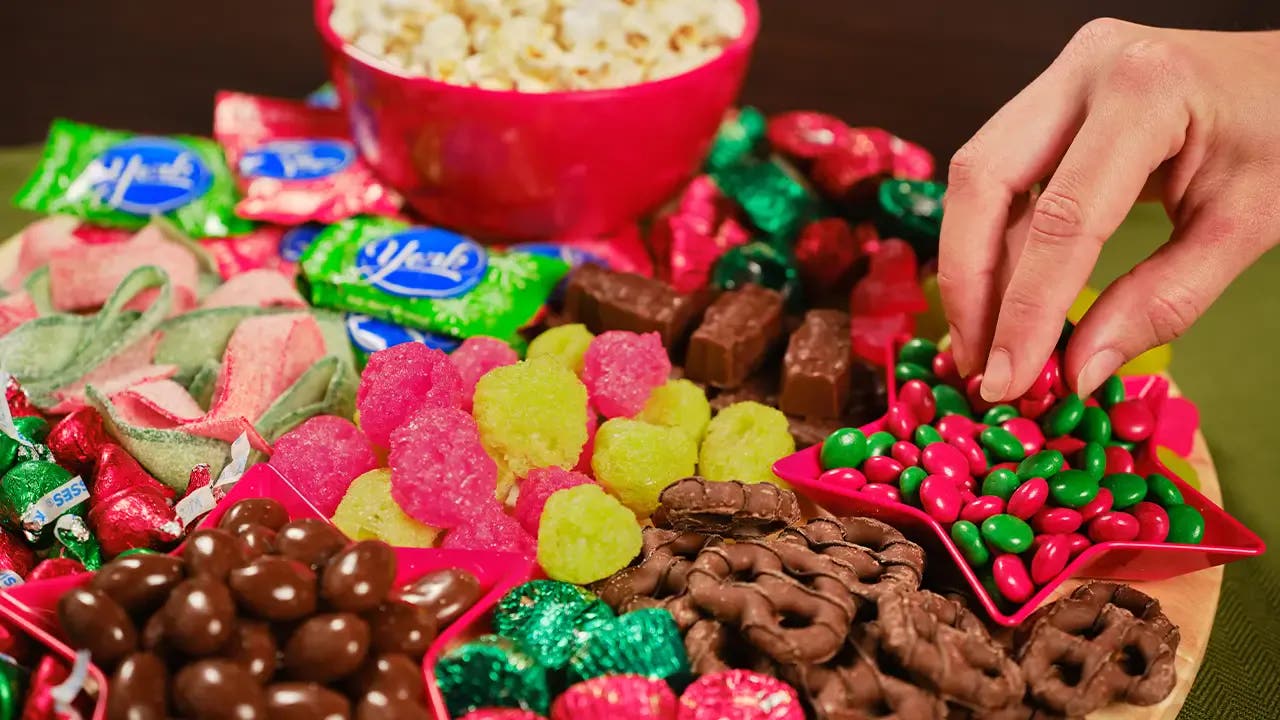 A hand picking up candy off of the board