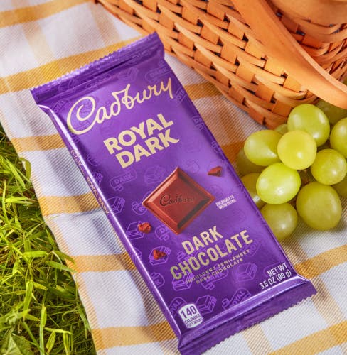 cadbury chocolate on picnic blanket next to plate of grapes
