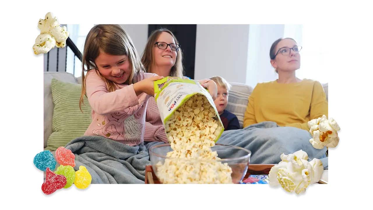 family sitting on a couch watching a movie and enjoying skinnypop popcorn