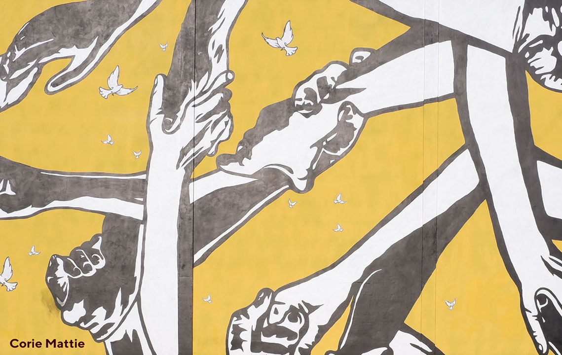mural of hands holding onto one another surrounded by birds
