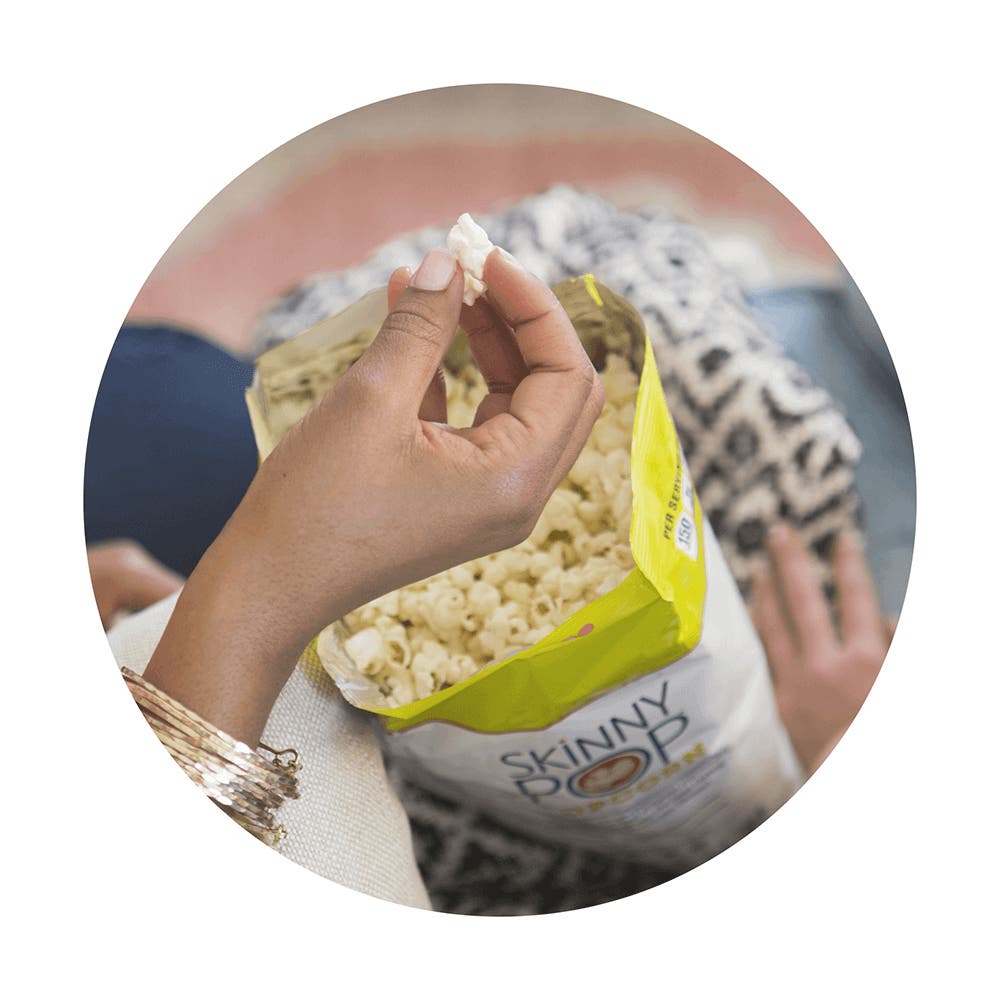 people eating and enjoying skinnypop popped popcorn on the couch