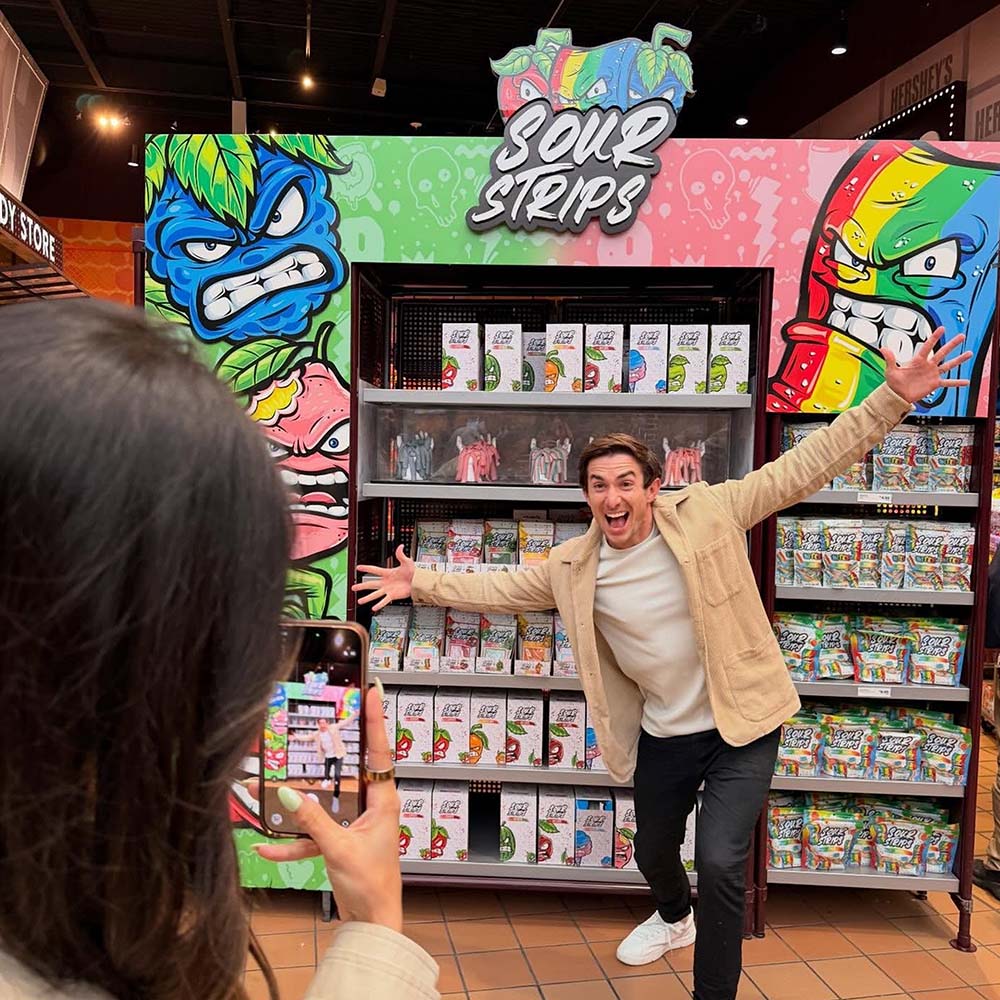 Maxx Chewning standing by sour strips display at hersheys chocolate world