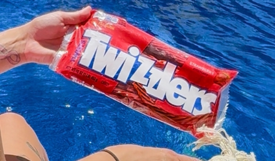 bag of twizzlers being held over blue water