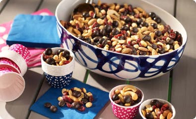 chocolate fruit and nuts trail mix in a bowl and in small paper cups