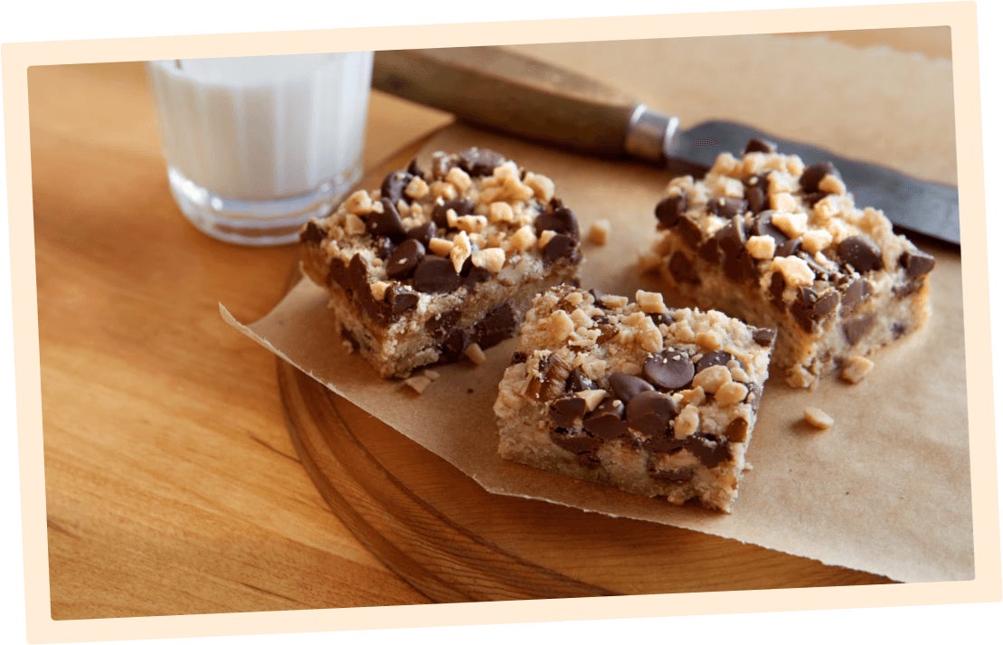 dessert bars on a wooden table by a glass of milk