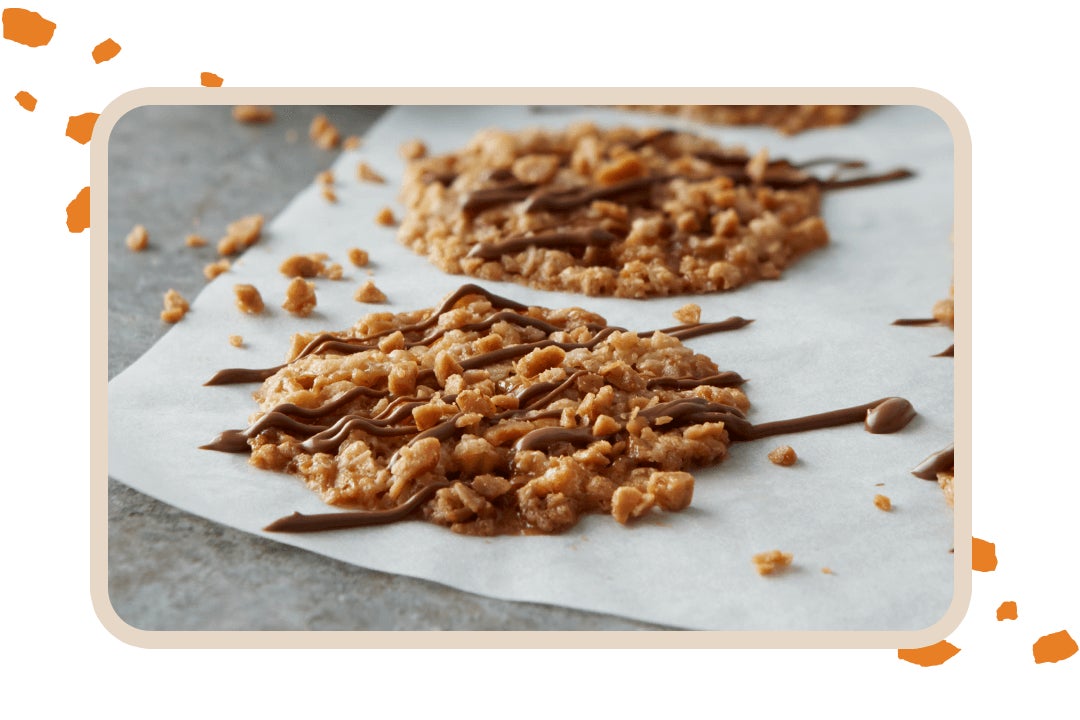 batch of heath toffee bits lace cookies cooling on parchment paper