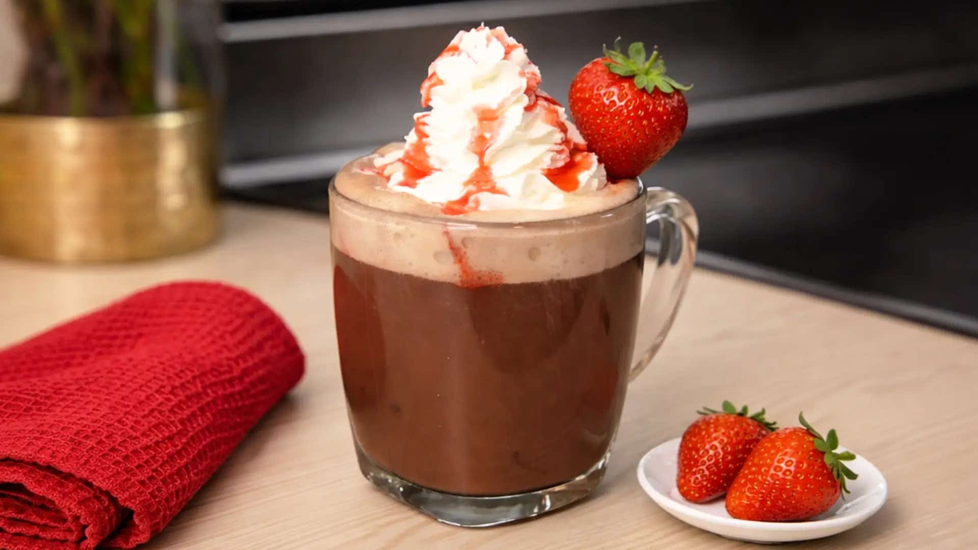 mug of strawberry hot chocolate topped with whipped cream and hersheys strawberry syrup