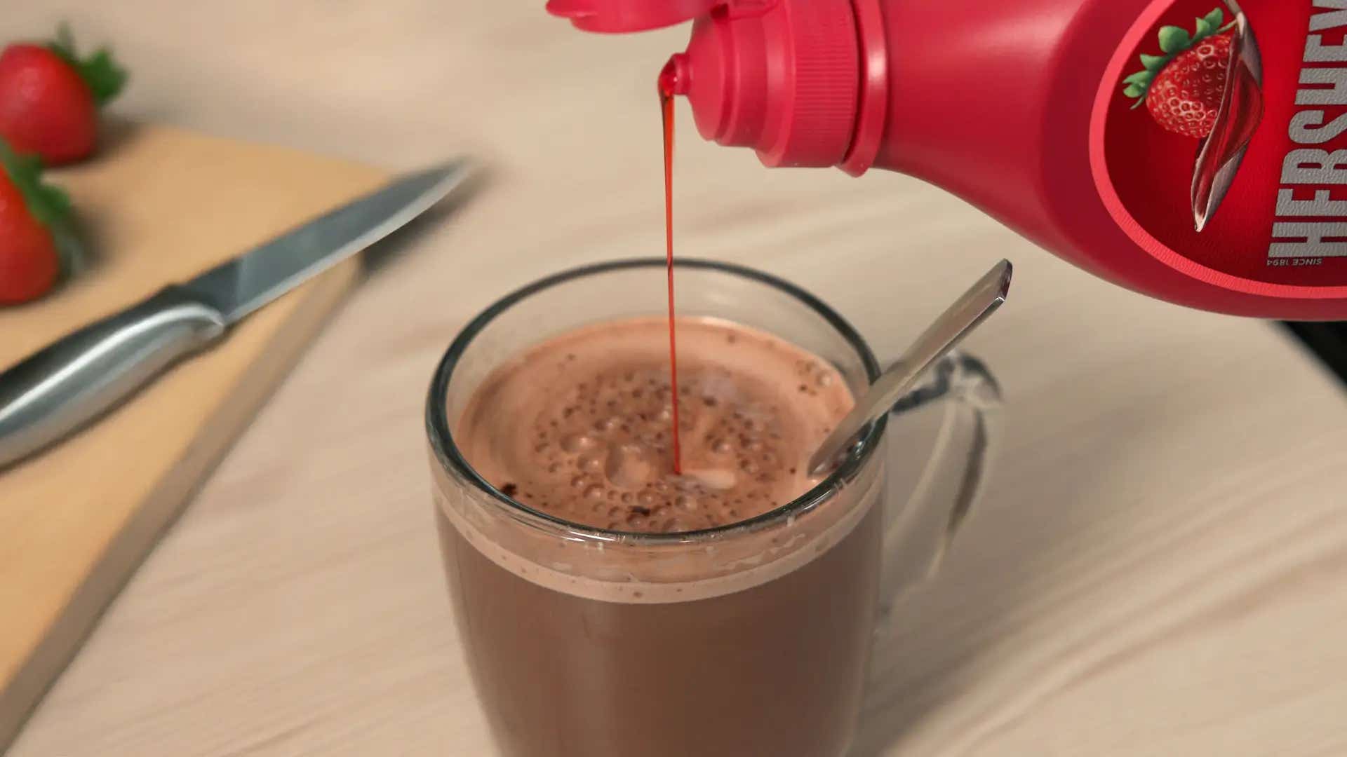 strawberry syrup being poured into mug