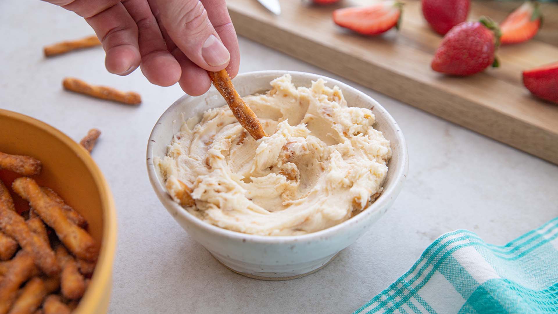 person dipping a dots pretzel into the dots cheesecake dip