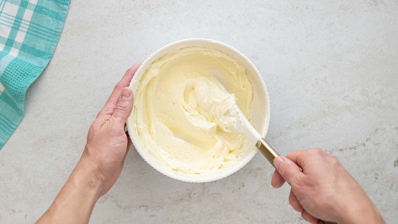 person beating cream cheese and butter together in a bowl