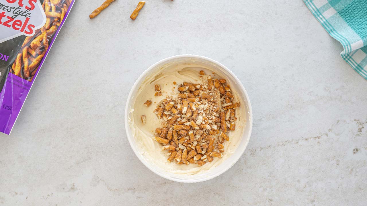 person adding pretzel pieces into the bowl