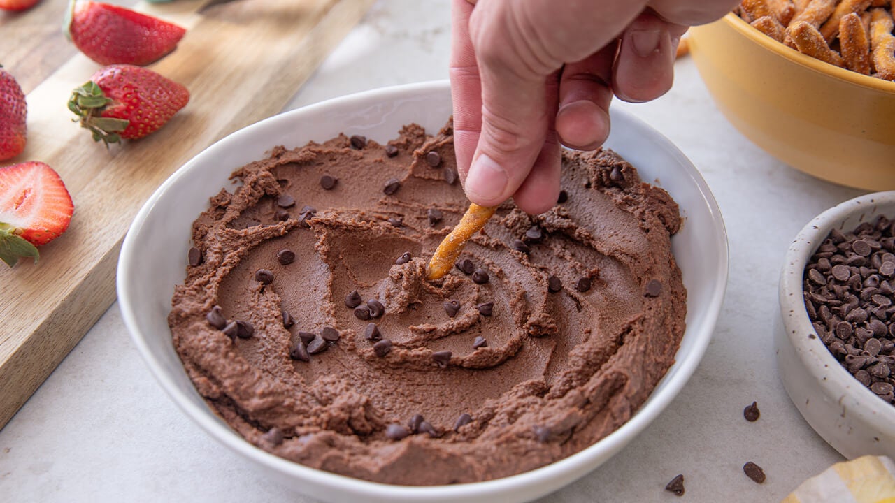 dipping pretzel in chocolate hummus