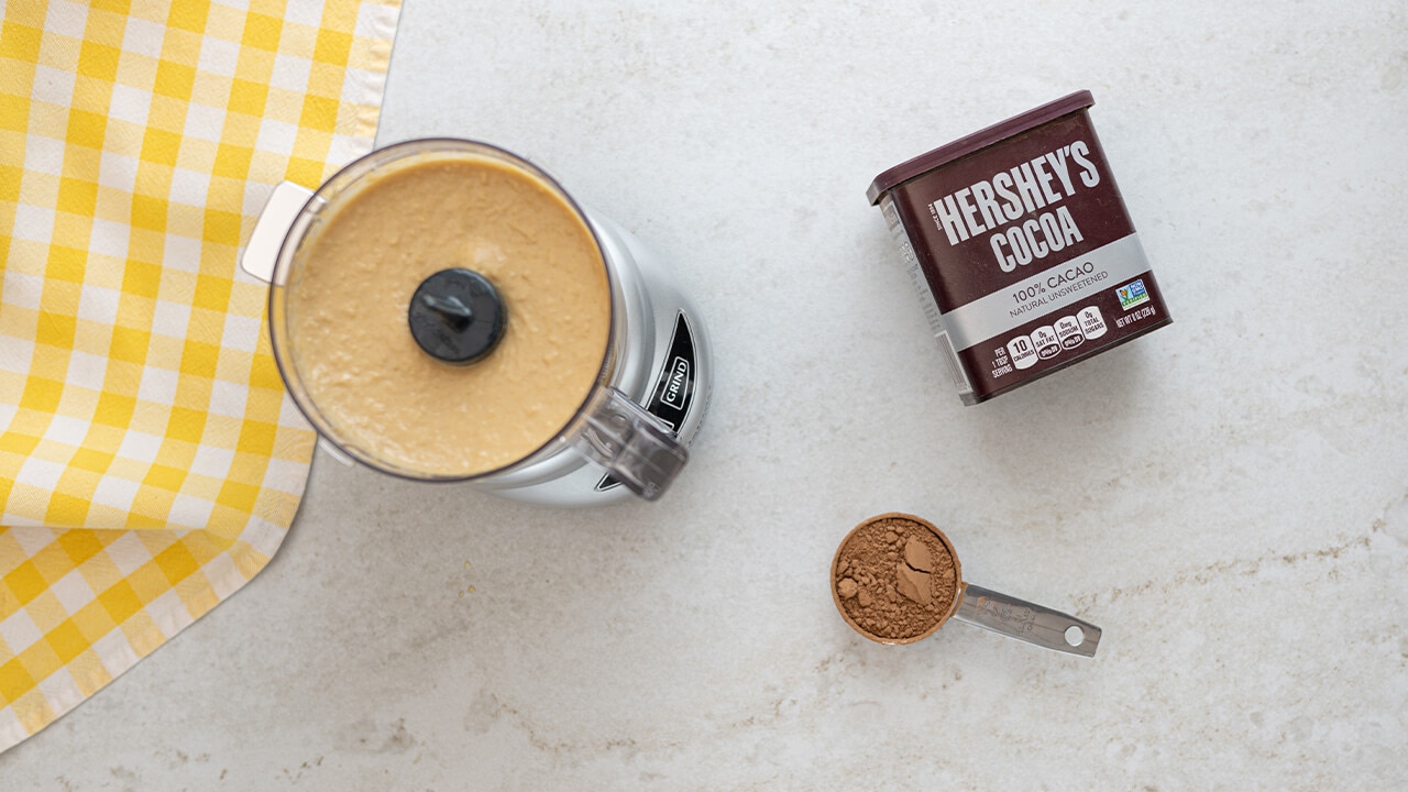 cocoa being added to hummus in food processor 