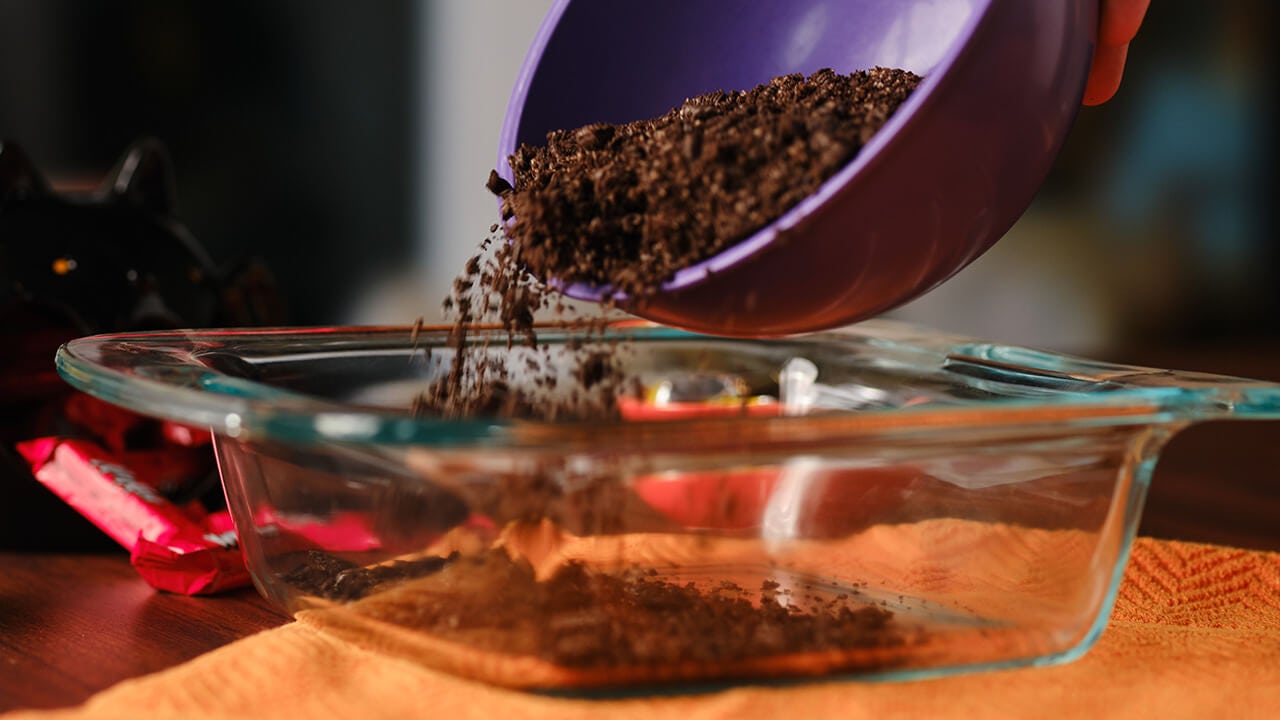 making layer of crushed cookies in tray