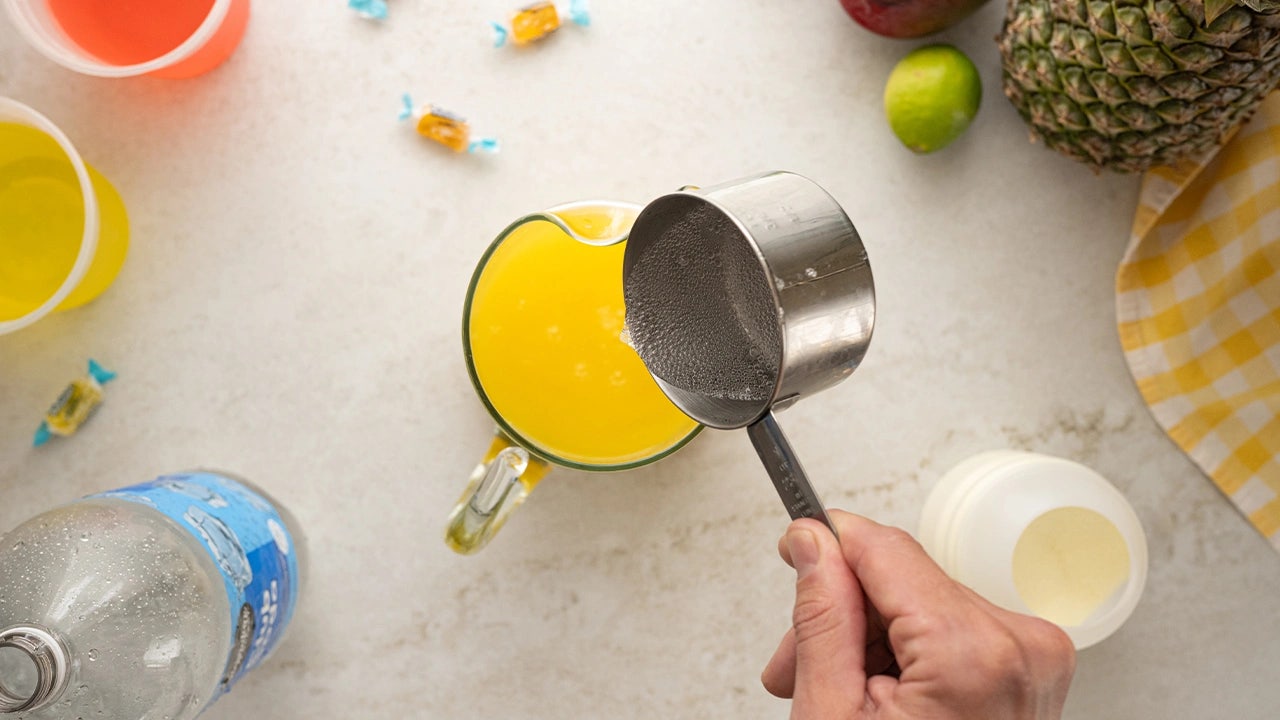 person adding seltzer water into the pitcher