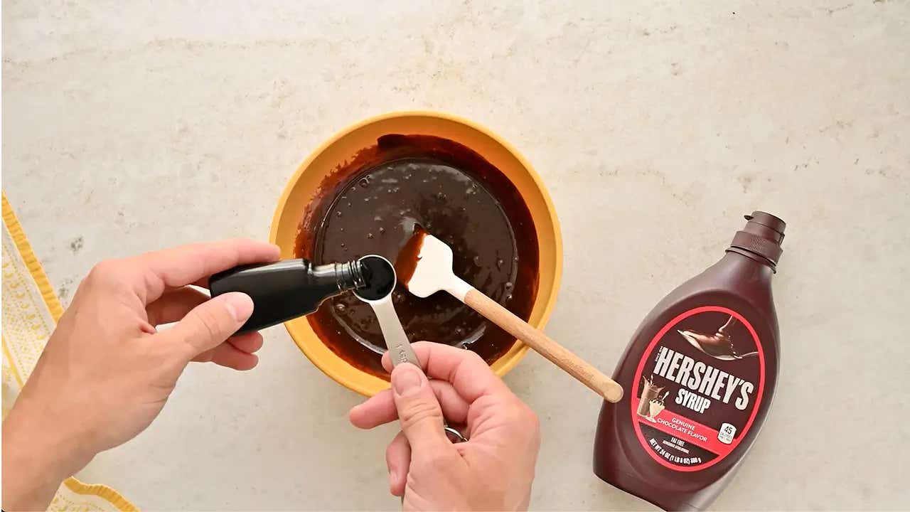 person adding vanilla extract into a mixing bowl