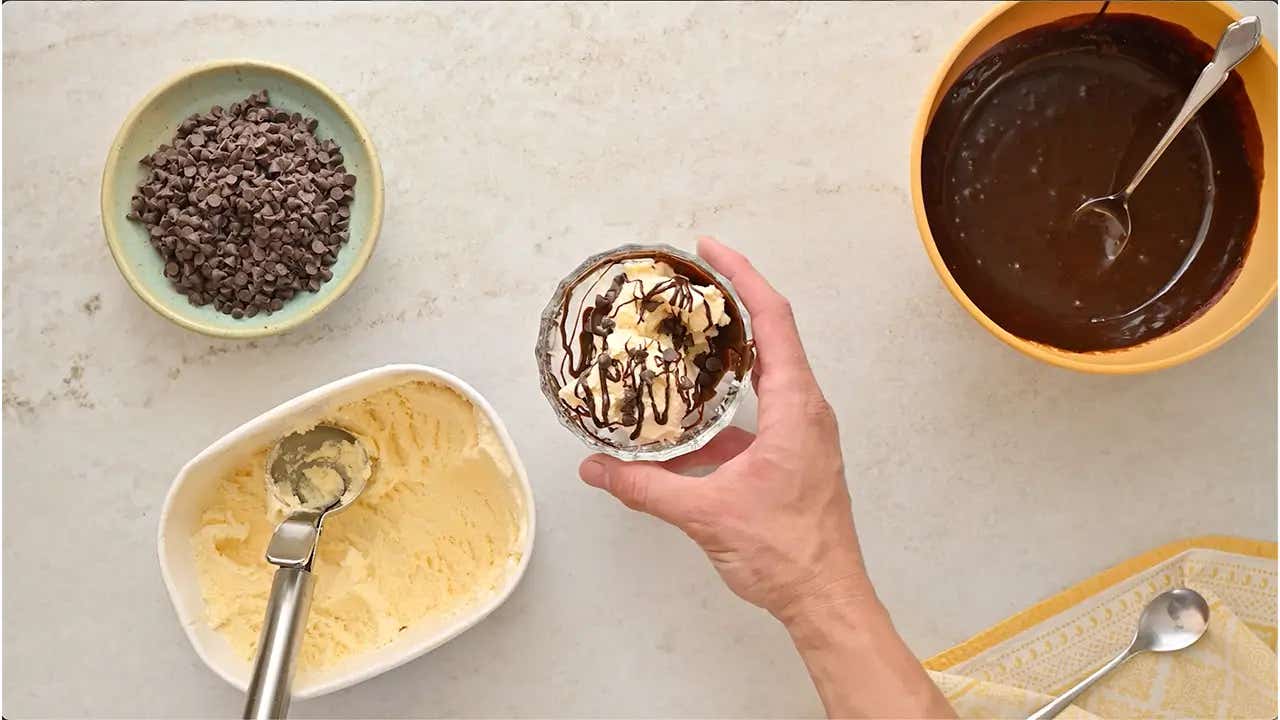 person holding the glass dessert cup filled with ingredients