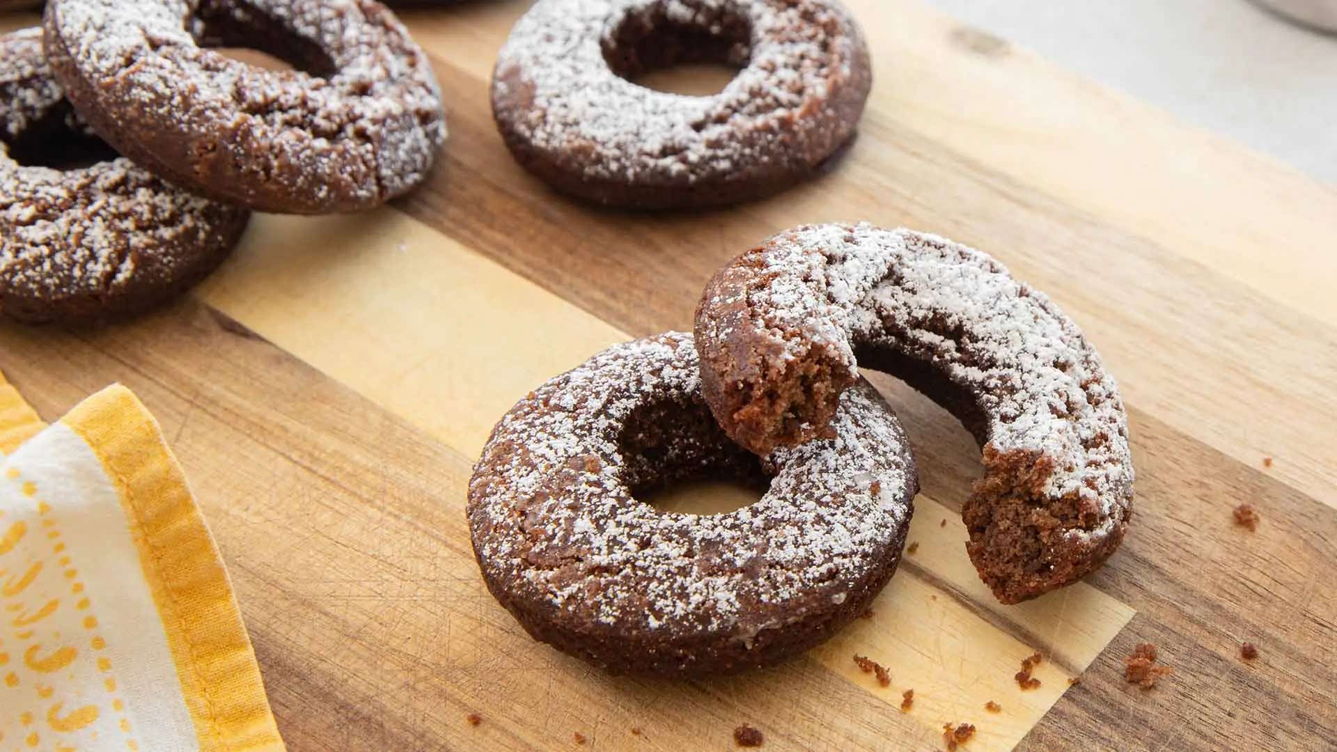powdered sugar dusted spiced cocoa doughnuts on wooden cutting board