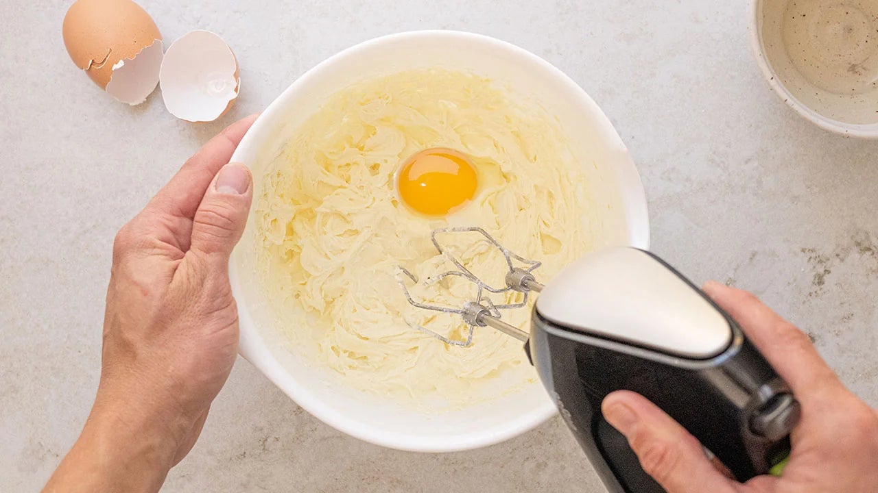 egg added to butter and sugar mixture in mixing bowl