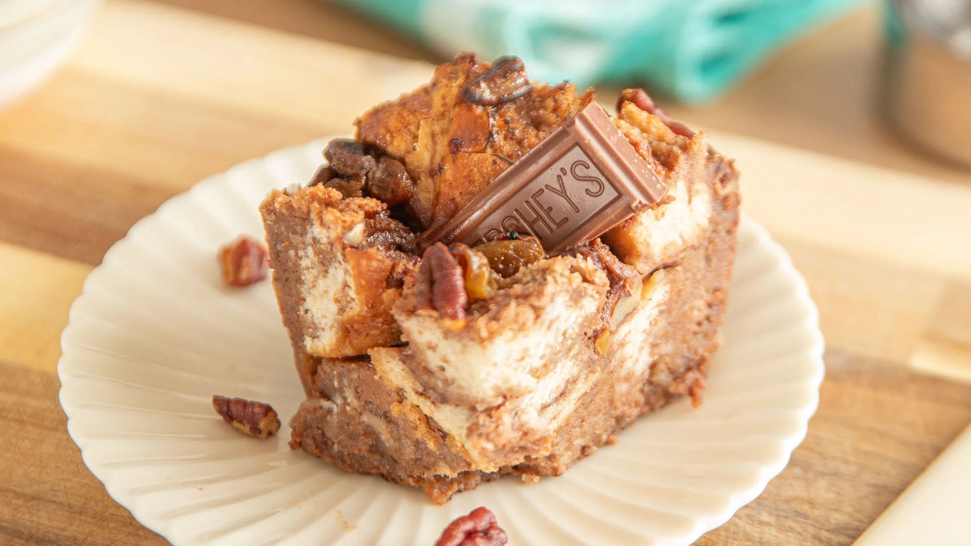 slice of chocolate bread pudding topped with a milk chocolate piece and pecans