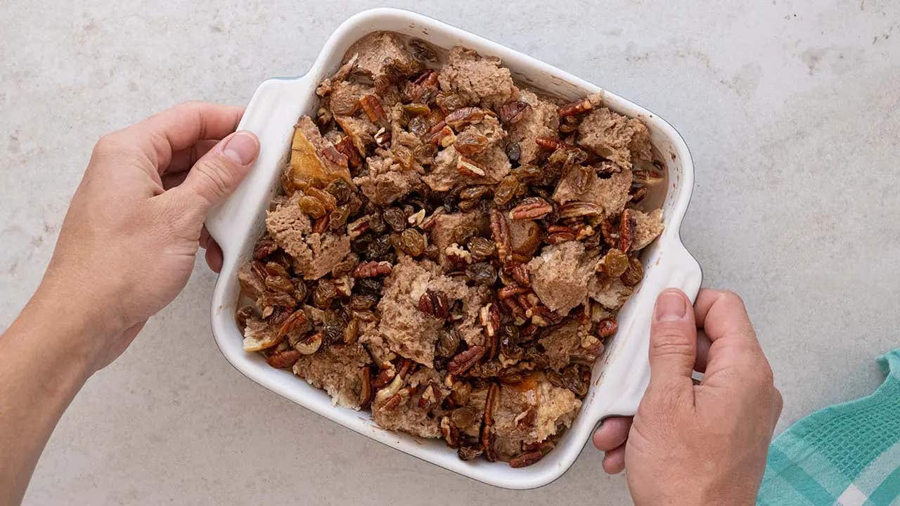 soaked bread topped with chopped pecans and raisins in casserole dish