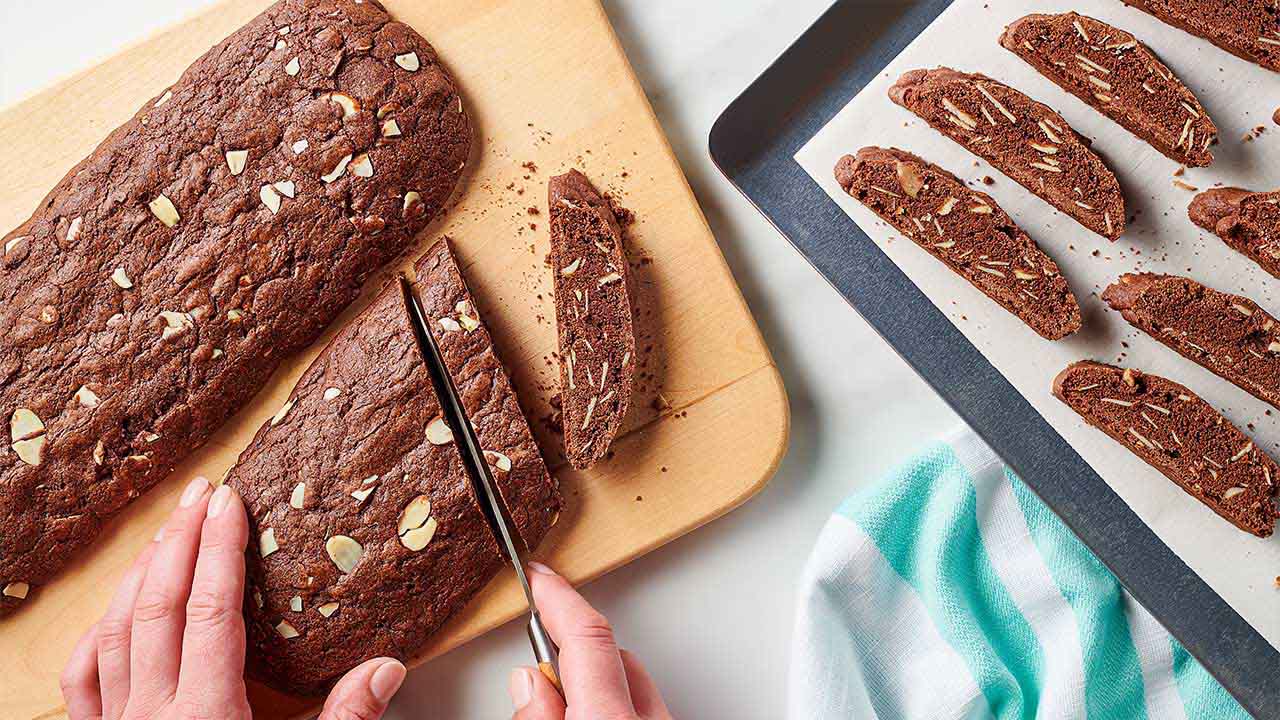 person slicing biscotti log into smaller strips