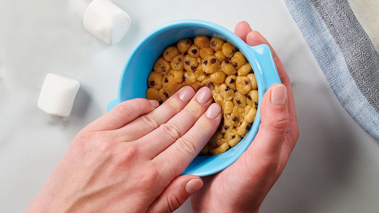 person spreading cookie dough bites out evenly in the ramekin dish