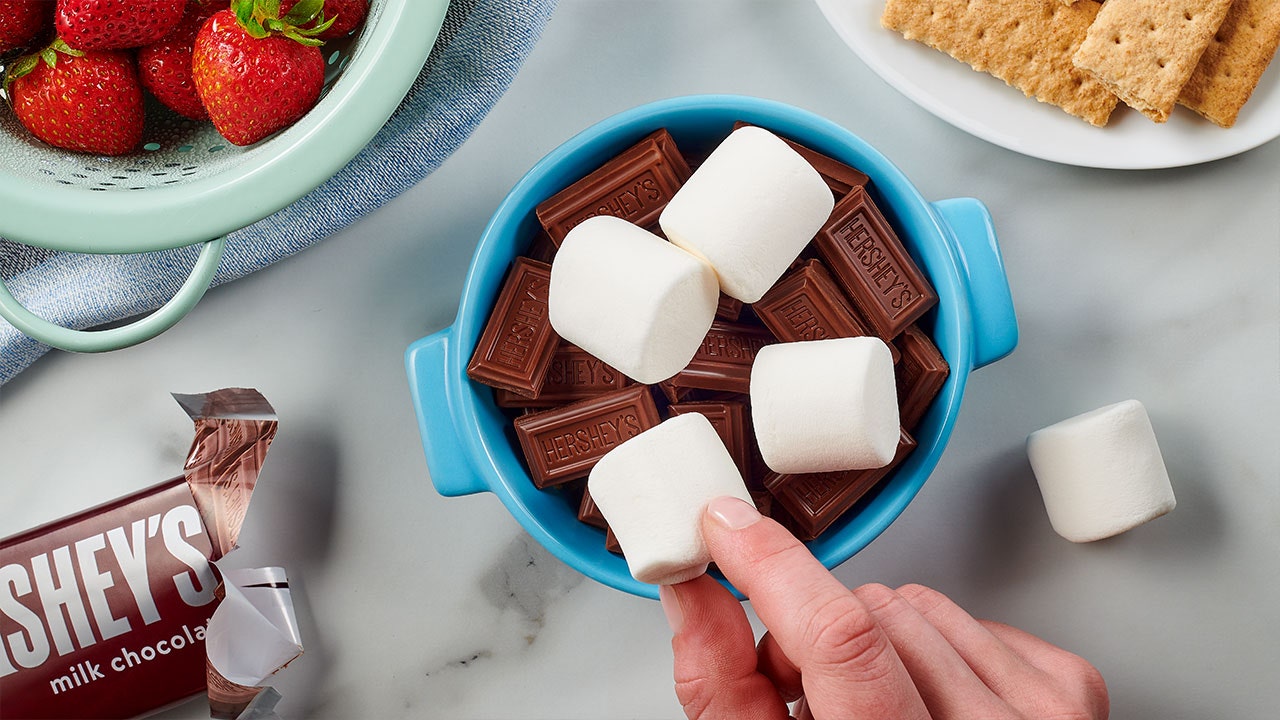 person placing marshmallows into the ramekin dish