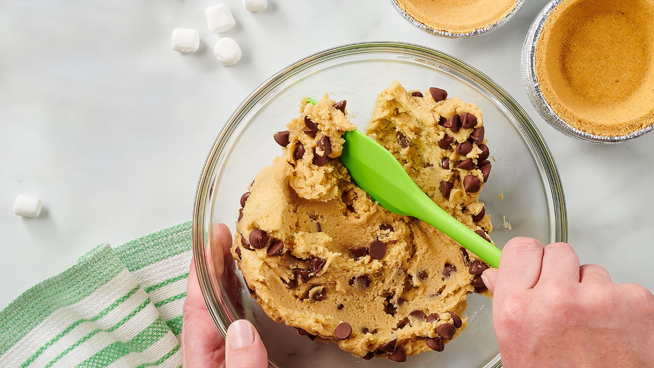 person mixing chocolate chips into cookie dough