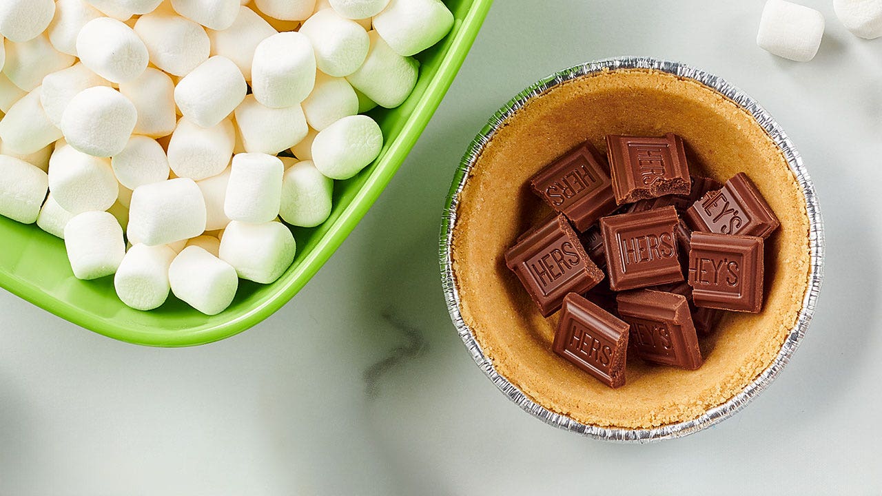 topping the mini pie shell with broken pieces of hersheys milk chocolate bars