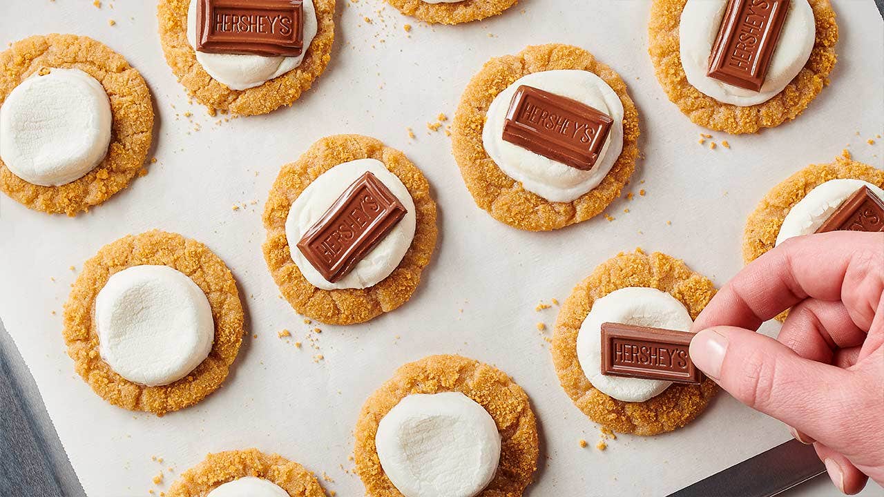 person topping each smores cookie with hersheys pips