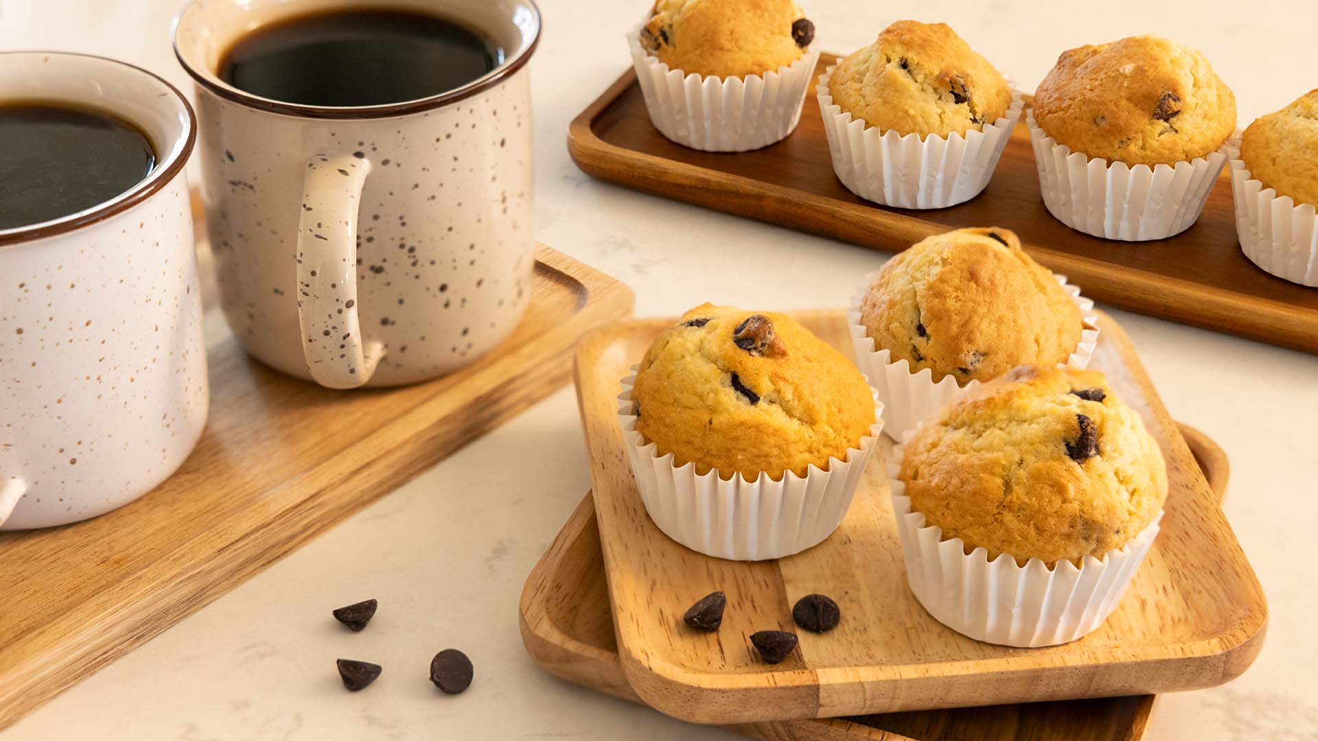 tray of fresh chocolate chip muffins and two mugs of hot coffee