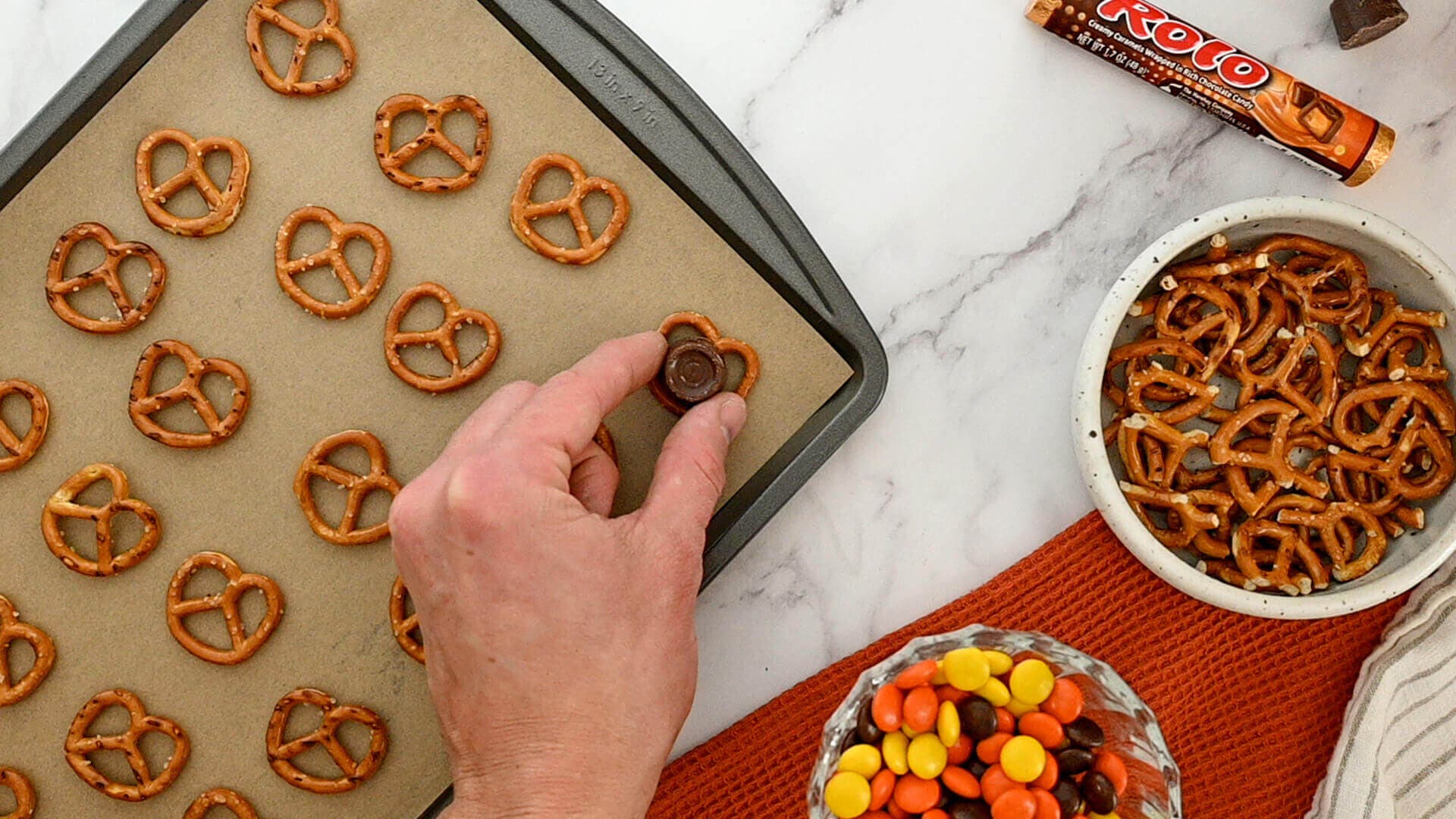 pretzels on cookie shete being topped with rolos