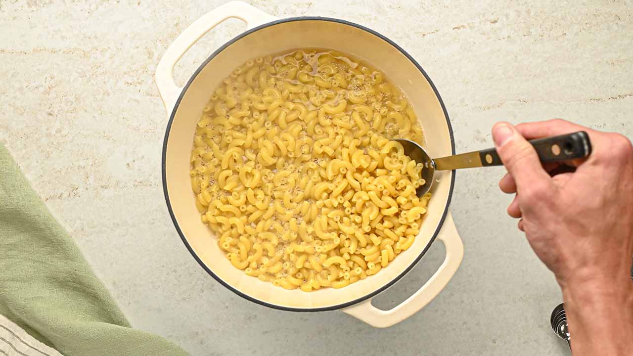 stirring the boiled macaroni in a large pot