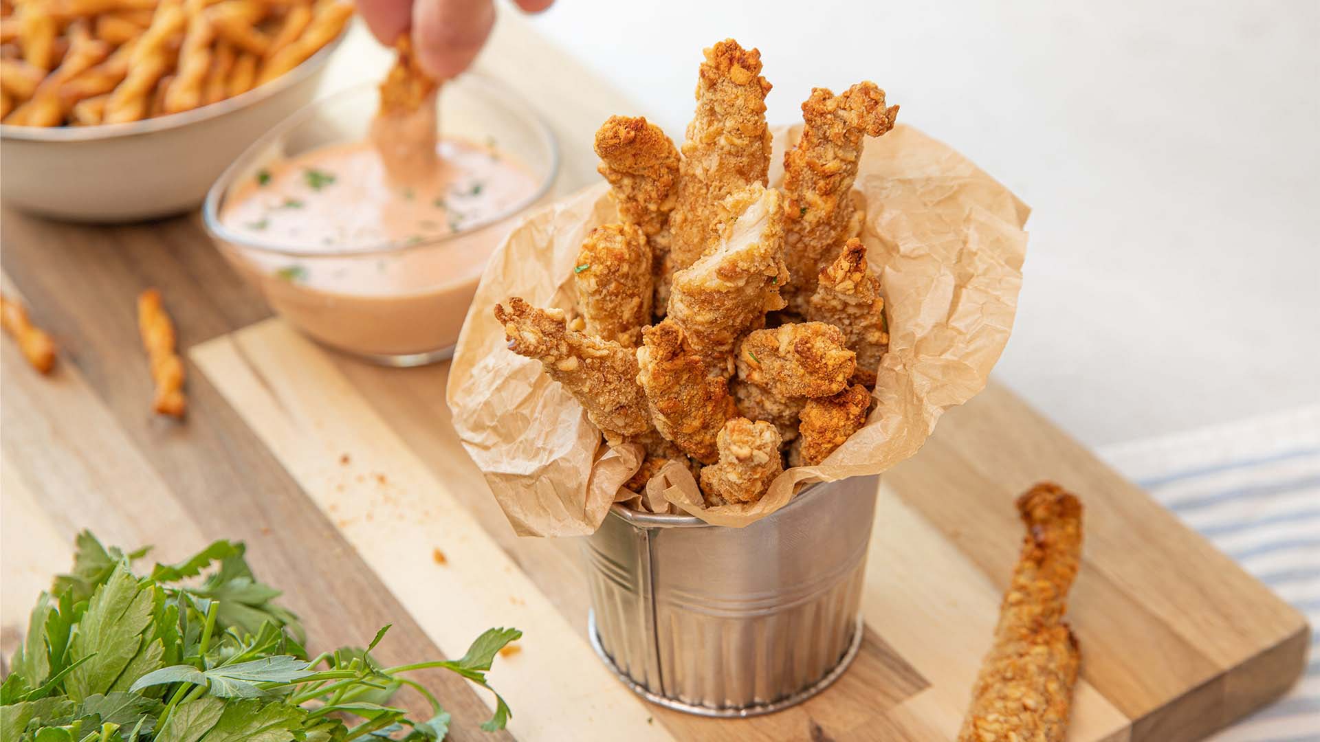 person dipping the dots pretzel crusted chicken strips into sauce